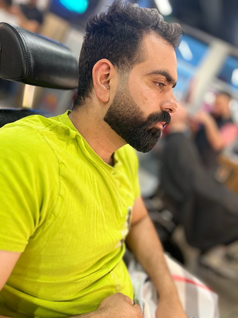 Man with dark beard wearing a bright neon yellow shirt, profile view in an indoor setting